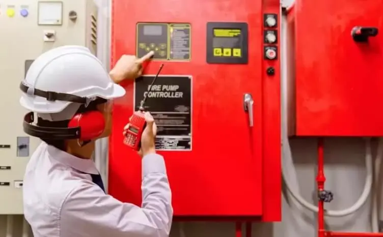 Técnica de capacete operando o painel de uma bomba de incêndio