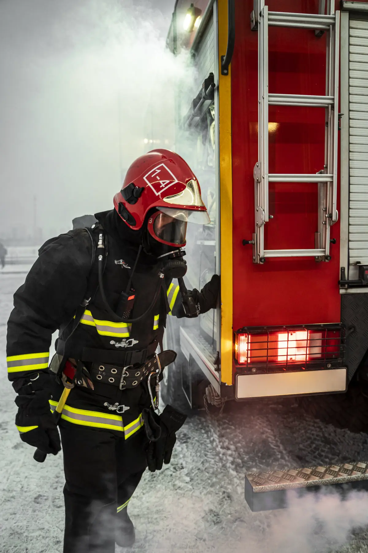 Bombeiro com equipamento de proteção ao lado de uma viatura de combate a incêndio